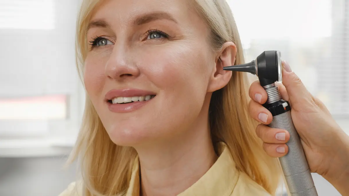 Medico che esamina l’orecchio di una donna con un otoscopio